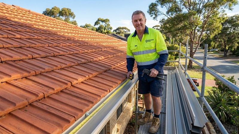 Roofing professional measuring and fitting new gutter system on a residential Perth property during installation